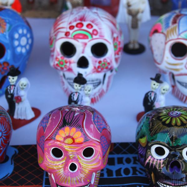 Colorfully painted sugar skulls—white skull shapes adorned with floral and decorative motifs in pink, red, and green.
